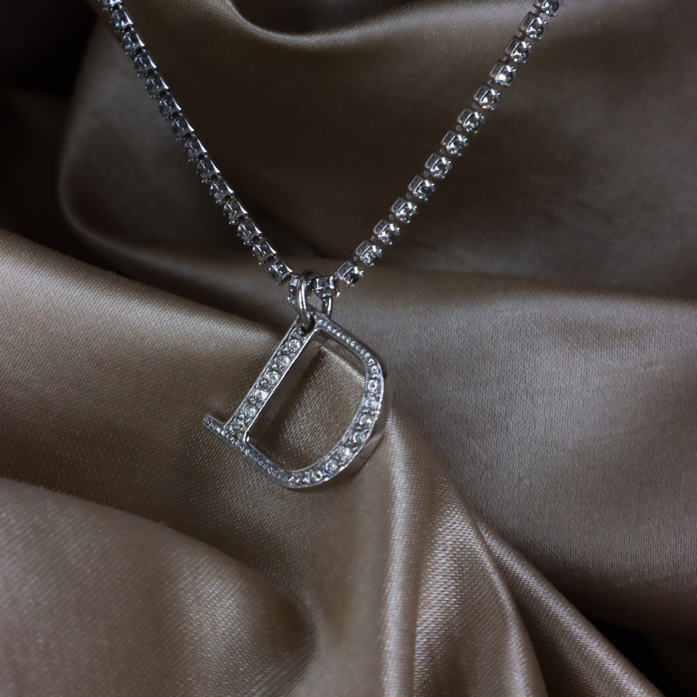 DIOR 銀色 D 字母鏤空吊墜特寫，展示透明石飾