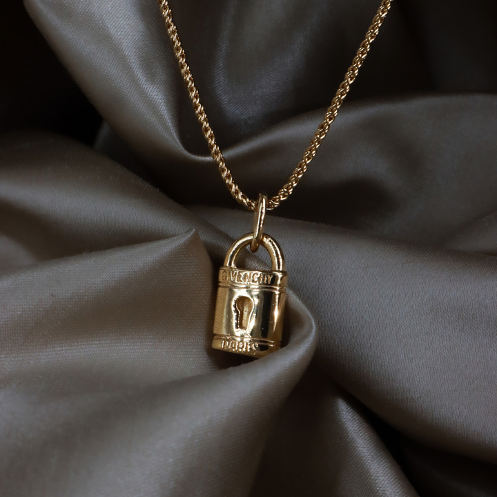 Givenchy 金色鎖頭吊墜項鏈正面特寫，展示 GIVENCHY 與 PARIS 刻字及亮面鎖身